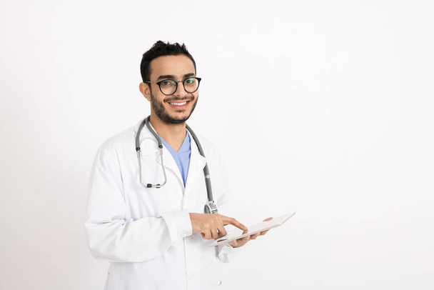 Junge erfolgreiche Ärztin mit Touchpad, während sie online medizinische Rezepte für Patienten vor der Kamera macht - Foto, Bild