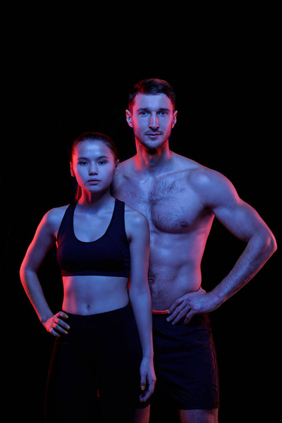 Mladí fit mužští a ženské sportovci v aktivním oblečení dívají na vás, zatímco stojí před kamerou v izolaci - Fotografie, Obrázek
