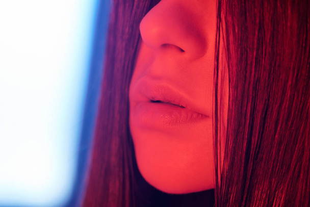 Close-up of seductive lips of brunette woman in neon light, temptation concept - Zdjęcie, obraz