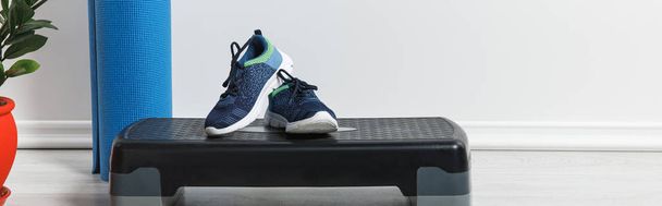 panoramisch shot van step platform, blauwe fitness mat en sneakers thuis  - Foto, afbeelding