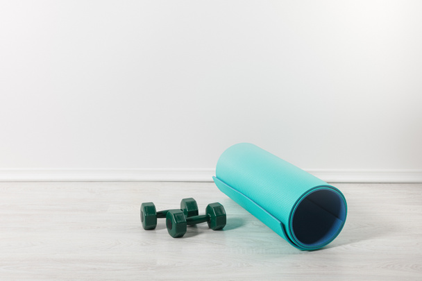 fitness mat and dumbbells on floor at home - Фото, изображение