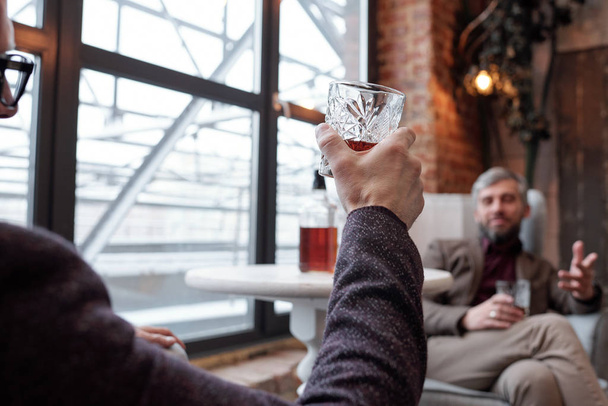 Przez ramię widok człowieka siedzi w restauracji i pije whisky z przyjacielem - Zdjęcie, obraz