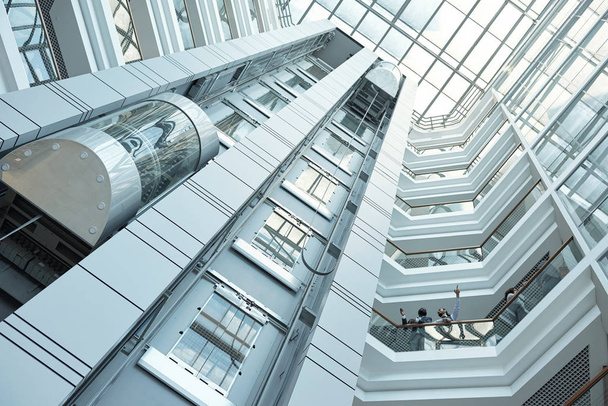 Hareket halindeki asansör, duvarlar ve arka plan olarak kullanılabilecek çağdaş iş merkezinin balkonları. - Fotoğraf, Görsel