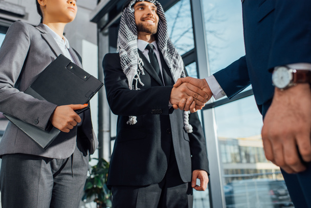 cheerful arabic businessman shaking hands with partner on meeting with translator in office - Photo, Image