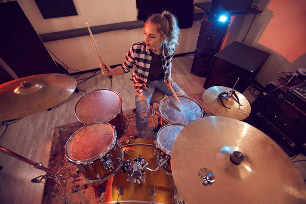 Портрет молодої жінки, що грає на барабанах у студії звукозапису, освітлений червоними вогнями, копіює простір
 - Фото, зображення