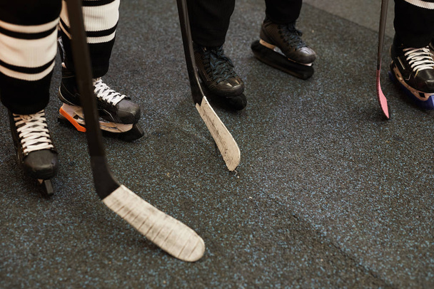 Background image of hockey team players ready for match in locker room, closeup shot of skating shoes and hockey clubs, copy space - Photo, Image