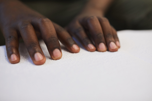 Nahaufnahme eines bis zur Unkenntlichkeit blinden Afrikaners, der während seines Studiums in der Schule Brailleschrift liest, Kopierraum - Foto, Bild