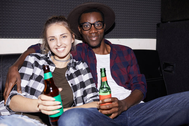 Портрет современной молодой пары, держащей пивные бутылки, наслаждающейся вечеринкой в ночном клубе, снятый вспышкой
 - Фото, изображение
