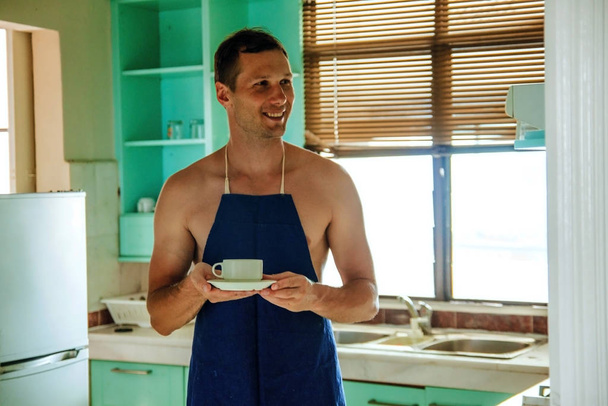 sexy muscular topless man in apron making coffee for breakfast in kitchen. - Valokuva, kuva