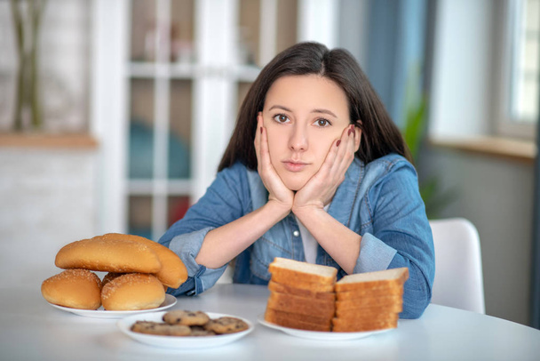 Nő nézi a tányérokat zsemlével és kenyérrel - Fotó, kép