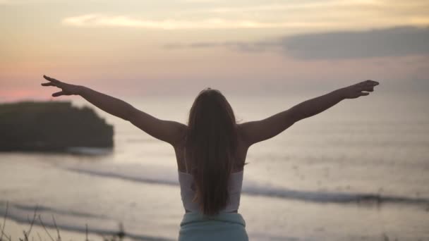 Mooi meisje biddend omhoog kijkend naar oranje lucht met hoop, close-up. Silhouet van jonge vrouw dromen kijken naar boven zonsondergang buiten oceaan achtergrond 4k. - Video
