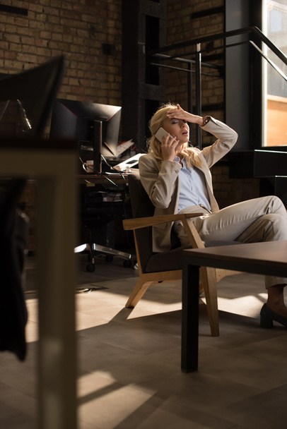 selective focus of tired business woman talking on smartphone while suffering from headache - Fotografie, Obrázek