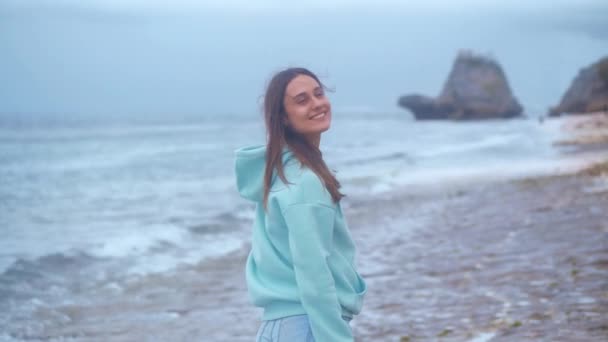 Muotokuva hipster nainen turkoosi huppari valtameren tausta hämärässä. 4 k.
 - Materiaali, video