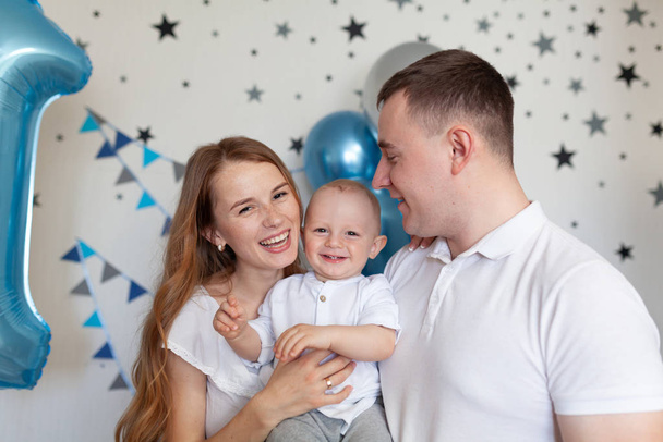 Portrait of happy mother, father and baby on the background of birthday decorationss - Fotoğraf, Görsel