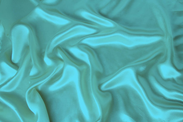 soft folds on delicate turquoise shining silk, luxury concept, background for the designer, horizontal, close-up, copy space - Photo, Image