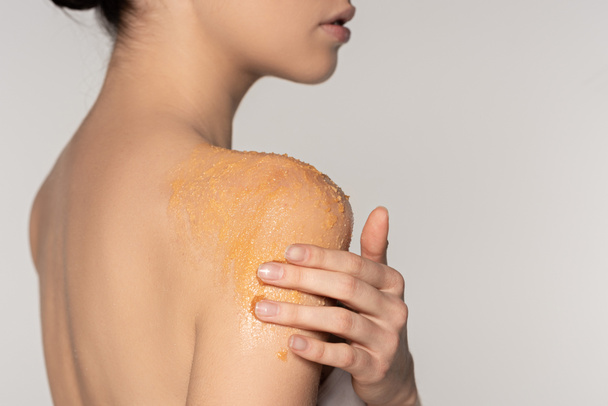 visão parcial da mulher aplicando esfoliação de sal no ombro, isolado em cinza
  - Foto, Imagem