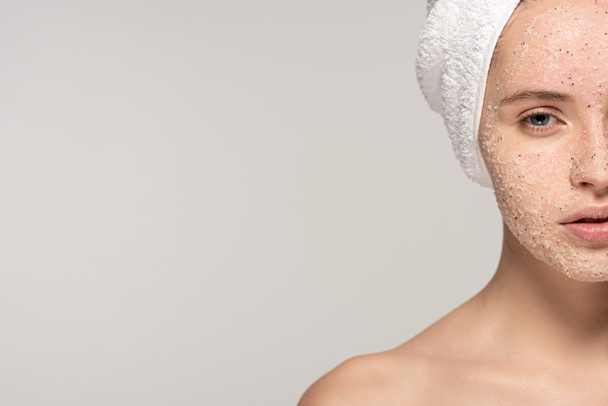 piękna dziewczyna z peelingiem kokosowym na twarzy i ręcznikiem na głowie, odizolowana na szaro - Zdjęcie, obraz