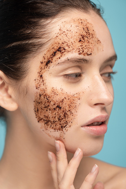 beautiful young woman applying coffee scrub on face, isolated on blue - Fotó, kép