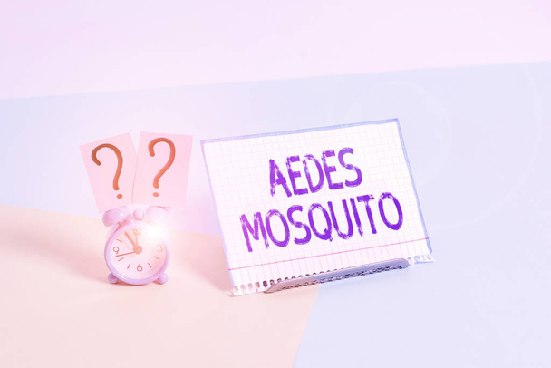 Teksten met Aedes Mosquito erop. Conceptuele foto de gele koorts mug die knokkelkoorts kan verspreiden Mini-size wekker naast een papieren laken geplaatst gekanteld op pastel achtergrond. - Foto, afbeelding