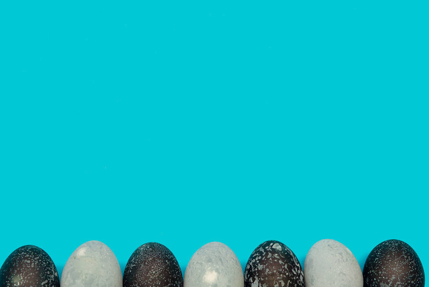Huevos de Pascua espacio pintado en la parte inferior de un fondo azul. Lugar para el texto. Tarjeta de Pascua
 - Foto, Imagen