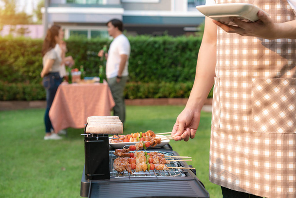 Asian man cooking barbeque grill and sausage for a group of frie - Photo, Image