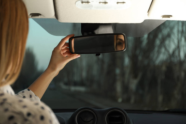 Young woman adjusting rear view mirror in car, closeup - Фото, зображення