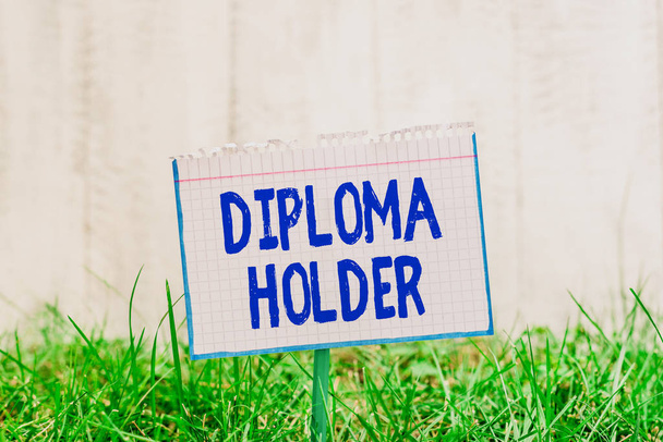 Word writing text Diploma Holder. Business concept for a demonstrating successfully completed a particular course of study Mathematic paper attached to a stick and placed in the green grassy land. - Photo, Image