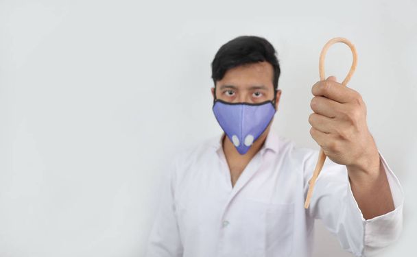 a medical professional in white coat and n 99 mask with a tourniquet in hand in white background with space for text - 写真・画像