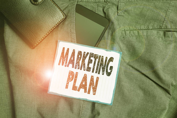 Znak tekstowy przedstawiający Plan Marketingu. Koncepcyjny dokument operacyjny zdjęcia przedstawiający strategię reklamową Smartfon wewnątrz kieszeni spodni z portfelem i papierem notatkowym. - Zdjęcie, obraz
