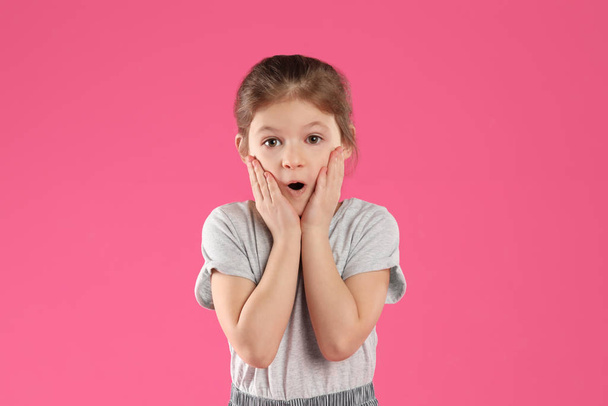 Portrait of shocked little girl on pink background - Foto, Imagem