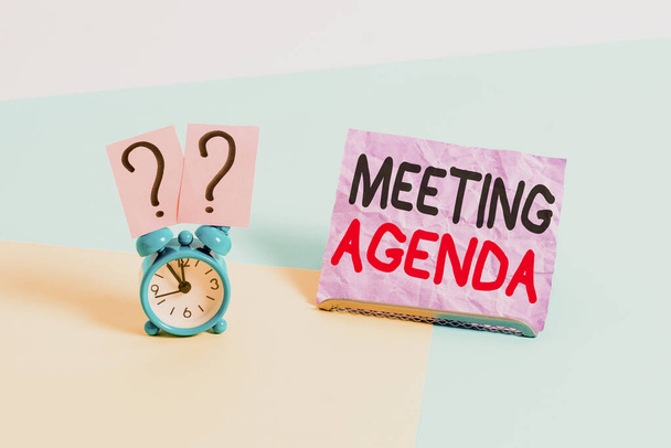 Handwriting text Meeting Agenda. Concept meaning list of items that participants to accomplish at a meeting Mini size alarm clock beside a Paper sheet placed tilted on pastel backdrop. - Fotoğraf, Görsel