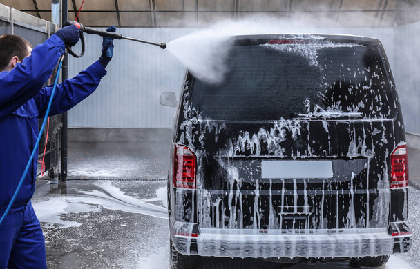 Worker cleaning automobile with high pressure water jet at car w - Fotó, kép