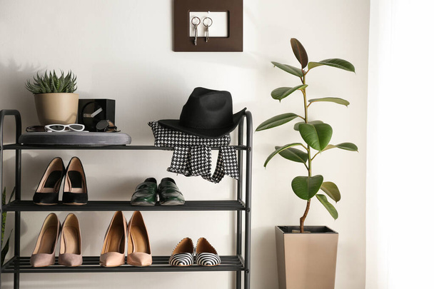 Black shelving unit with shoes and different accessories near wh - Photo, Image