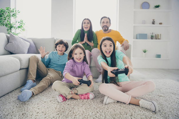 Portrait of nice attractive glad crazy excited ecstatic big full cheerful cheery family pre-teen kids playing video game having fun at light white interior style house apartment living-room - Photo, Image