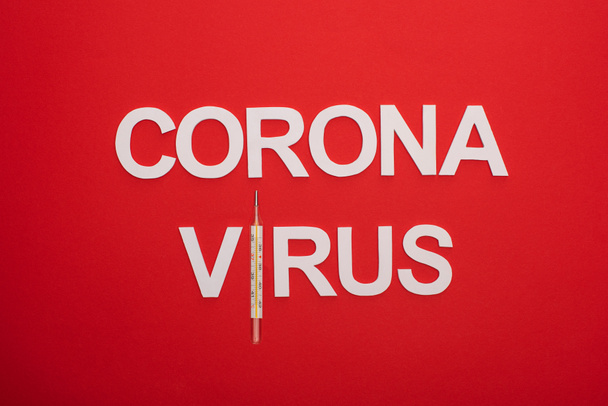 Vue du dessus du lettrage du coronavirus avec thermomètre isolé sur rouge
 - Photo, image