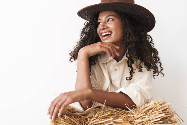 Beautiful smiling young african cowgirl sitting on a haystack - Фото, зображення