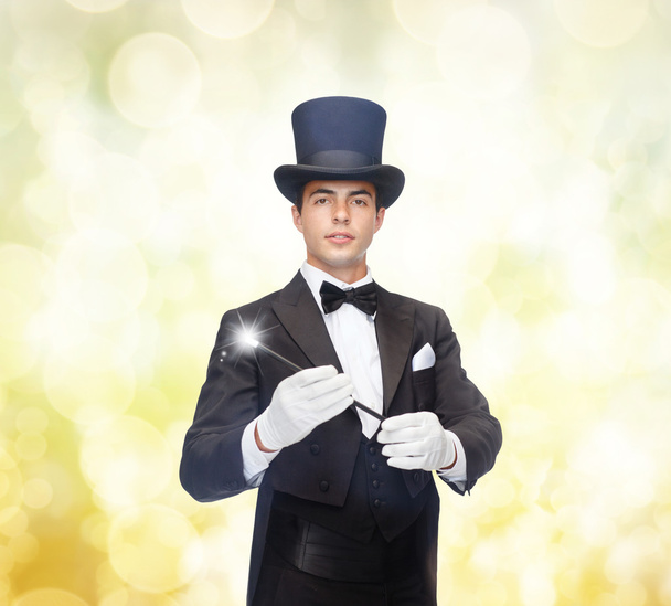 Magician in top hat with magic wand showing trick - Foto, Imagem