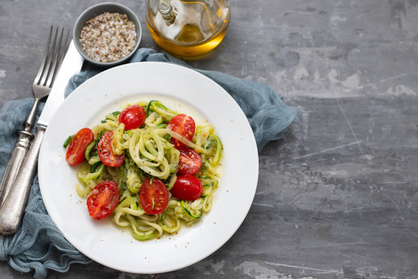 Spiral zucchini noodles with tomato on white plate on ceramic ba - Foto, imagen