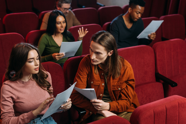 multietničtí herci a herečky čtou scénáře na sedadlech v divadle - Fotografie, Obrázek