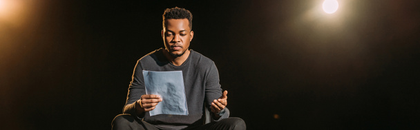 панорамный снимок африканского актера, держащего сценарий на сцене во время репетиции
  - Фото, изображение