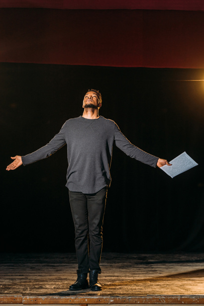 emotional african american actor holding scenario on stage during rehearse  - Foto, Imagen