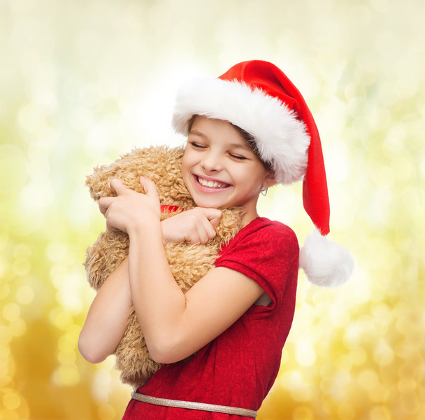 Smiling girl in santa helper hat with teddy bear - Valokuva, kuva