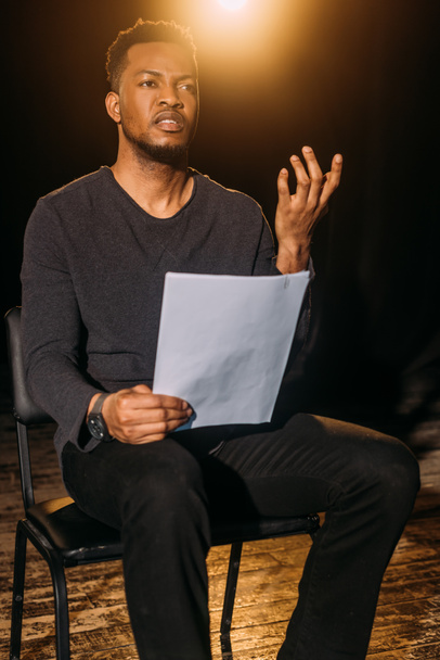 gutaussehender afrikanisch-amerikanischer Schauspieler hält Szenarium während der Probe auf der Bühne  - Foto, Bild