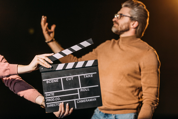 selective focus of mature actor performing role with clapboard in front  - Photo, Image