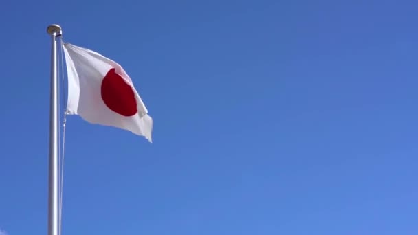 Real-time video japonské národní vlajky vlnící se ve větru proti bezmračné modré obloze v Japonsku, kde Tokio je hostitelským městem pro mezinárodní sportovní akce v létě 2020. - Záběry, video