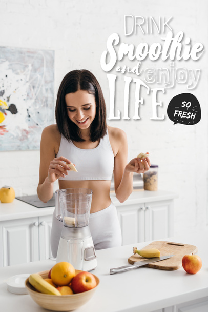 Beautiful smiling sportswoman putting banana in blender while preparing smoothie near drink smoothie and enjoy life illustration - Zdjęcie, obraz