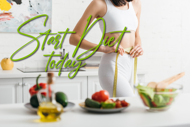 Selective focus of slim woman measuring waist with tape near fresh vegetables and salad on table, start diet today illustration - Photo, image