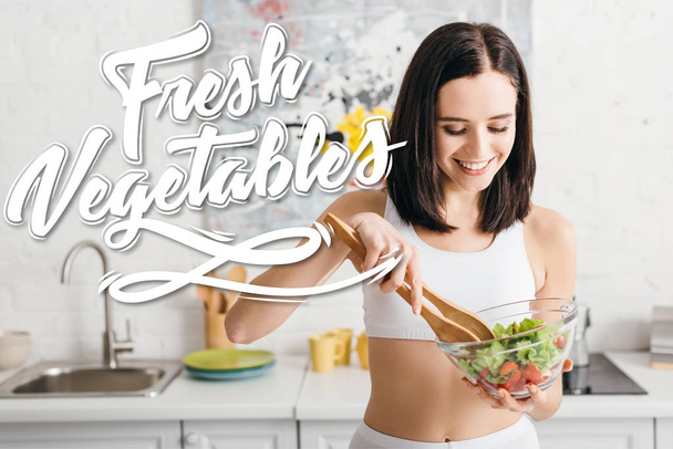 Attraktiv fitte Sportlerin lächelt beim Mischen von Salat in der Küche, frisches Gemüse Illustration - Foto, Bild