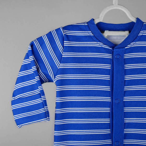 ハンガーには濃い青のストライプの赤ちゃん服がかかっています。服、母親、新生児の概念. - 写真・画像