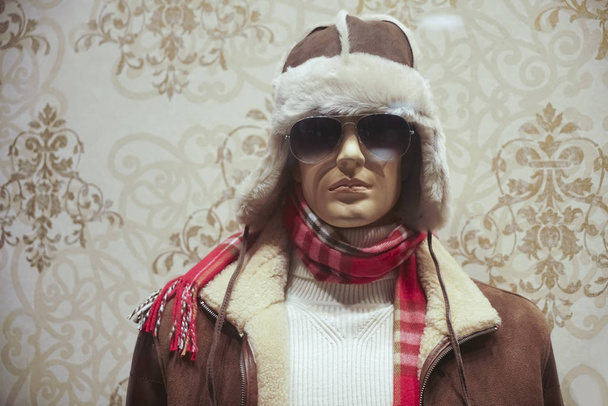 Male mannequin in knitted sweater, sunglasses, fur jacket , leather hat and red scarf, casual clothes. winter season.  - Fotoğraf, Görsel